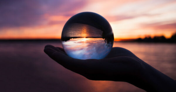 EXPLORE YOUR VALUES - Beautiful scenic view through lens of crystal ball on water horizon at summer sunset.